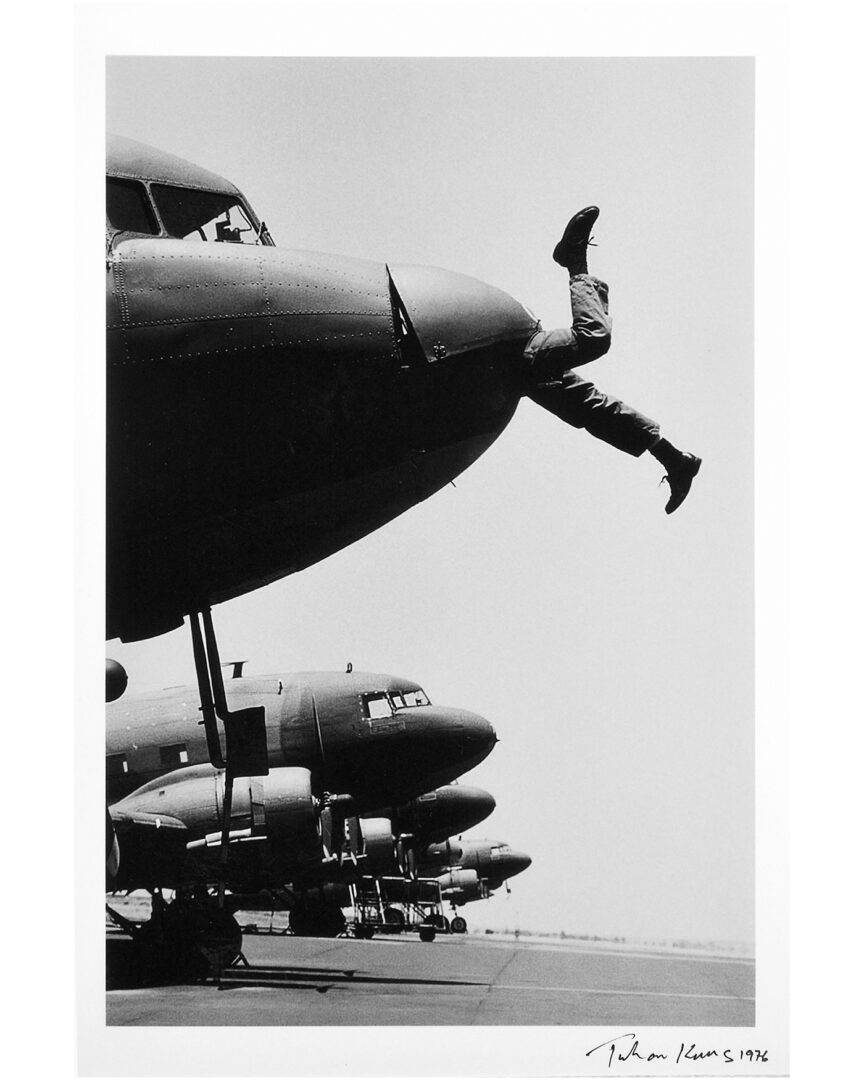 Black-and-white photo of a mans legs sticking out of the engine of an aeroplane. Taken by Juhan Kuus in 1976.
